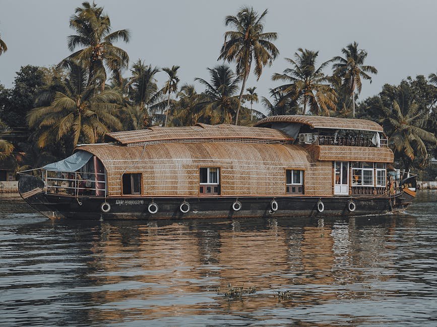 Houseboat traditionnel naviguant dans un canal borde de palmiers au Kerala