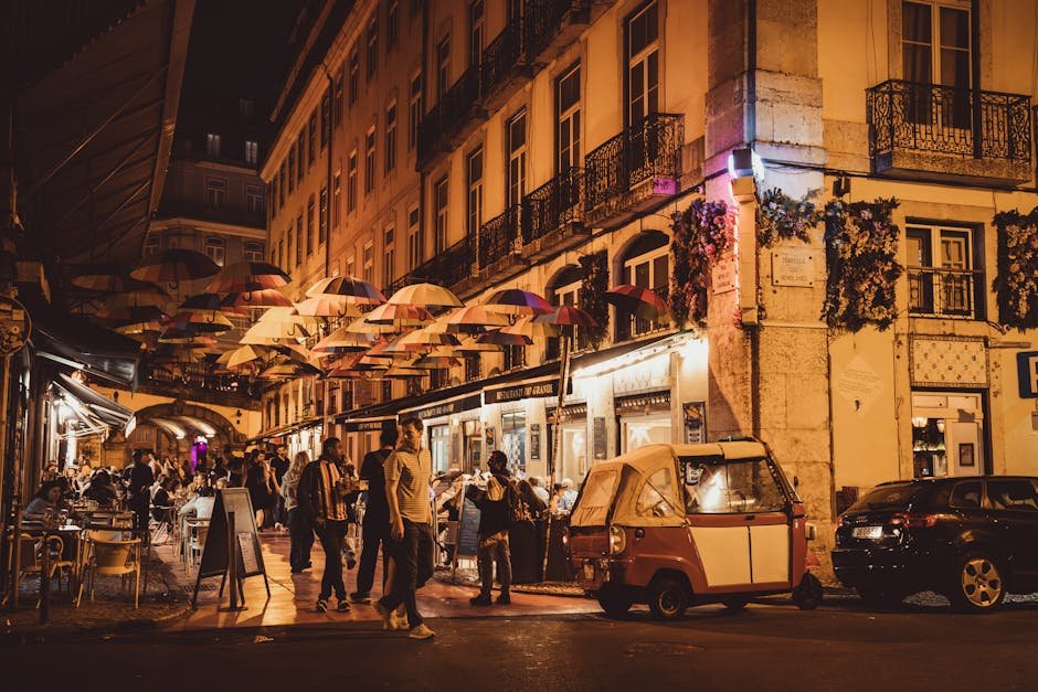 Terrasses de cafés sous des parasols illuminés dans une ruelle de Lisbonne