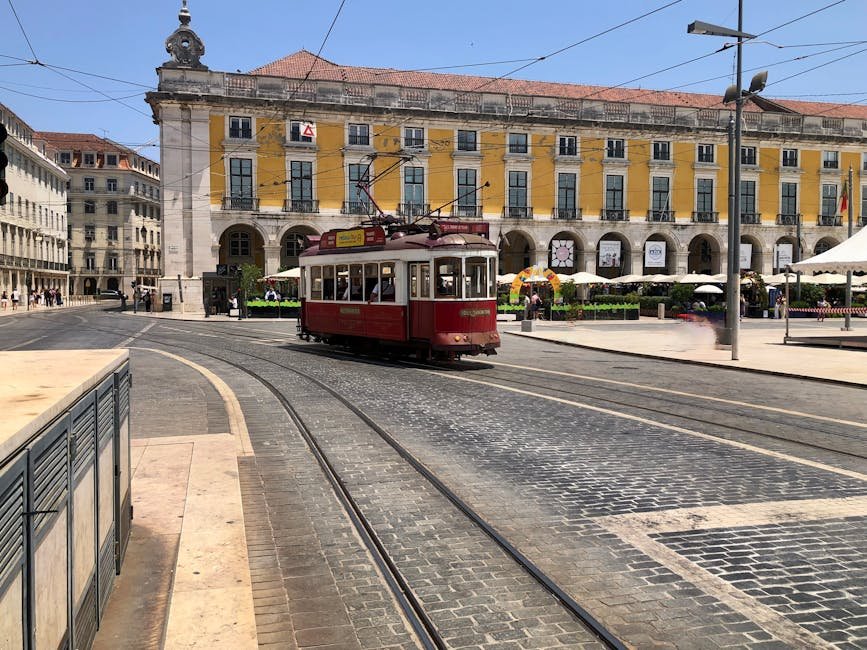 Tramway rouge passant devant la Praça do Comércio à Lisbonne sous le soleil