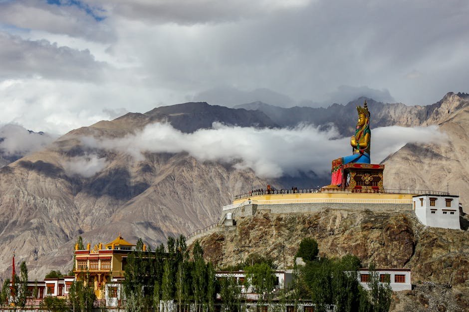 Statue dorée de Bouddha devant un monastère avec les montagnes de l'Himalaya en arrière-plan